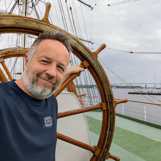Daniel Weihmann an Deck eines Segelschiffs, im Hintergrund die Rügenbrücke.