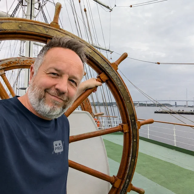Daniel Weihmann an Deck eines Segelschiffs, im Hintergrund die Rügenbrücke.